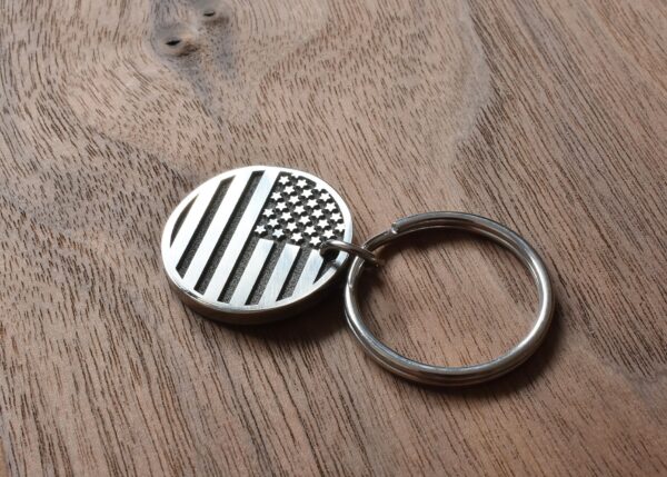 USA flag keychain on wooden surface, highlighting patriotic design and American craftsmanship.