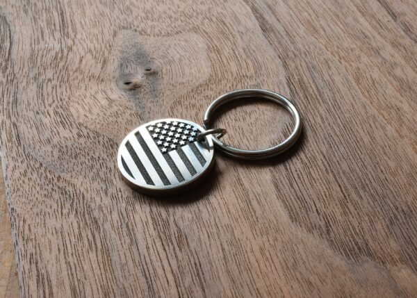 American flag keychain on wooden surface, patriotic accessory for keys or bags.