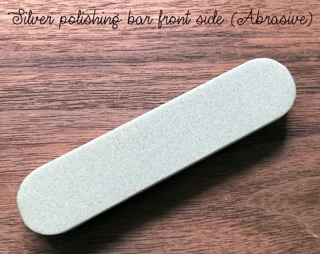 Silver polishing bar with abrasive surface on a wooden background.