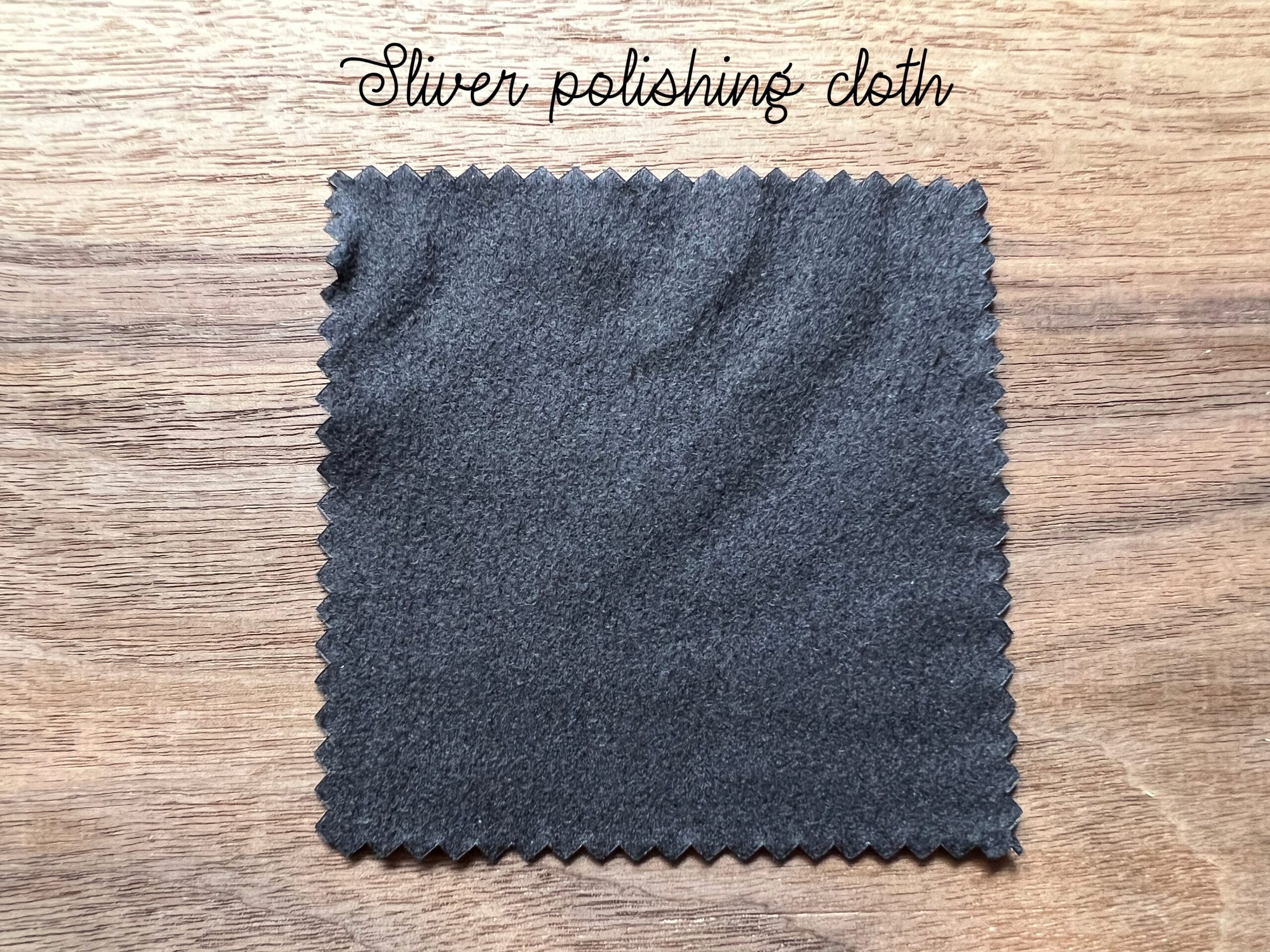 Gray silver polishing cloth on a wooden surface, labeled Silver polishing cloth.