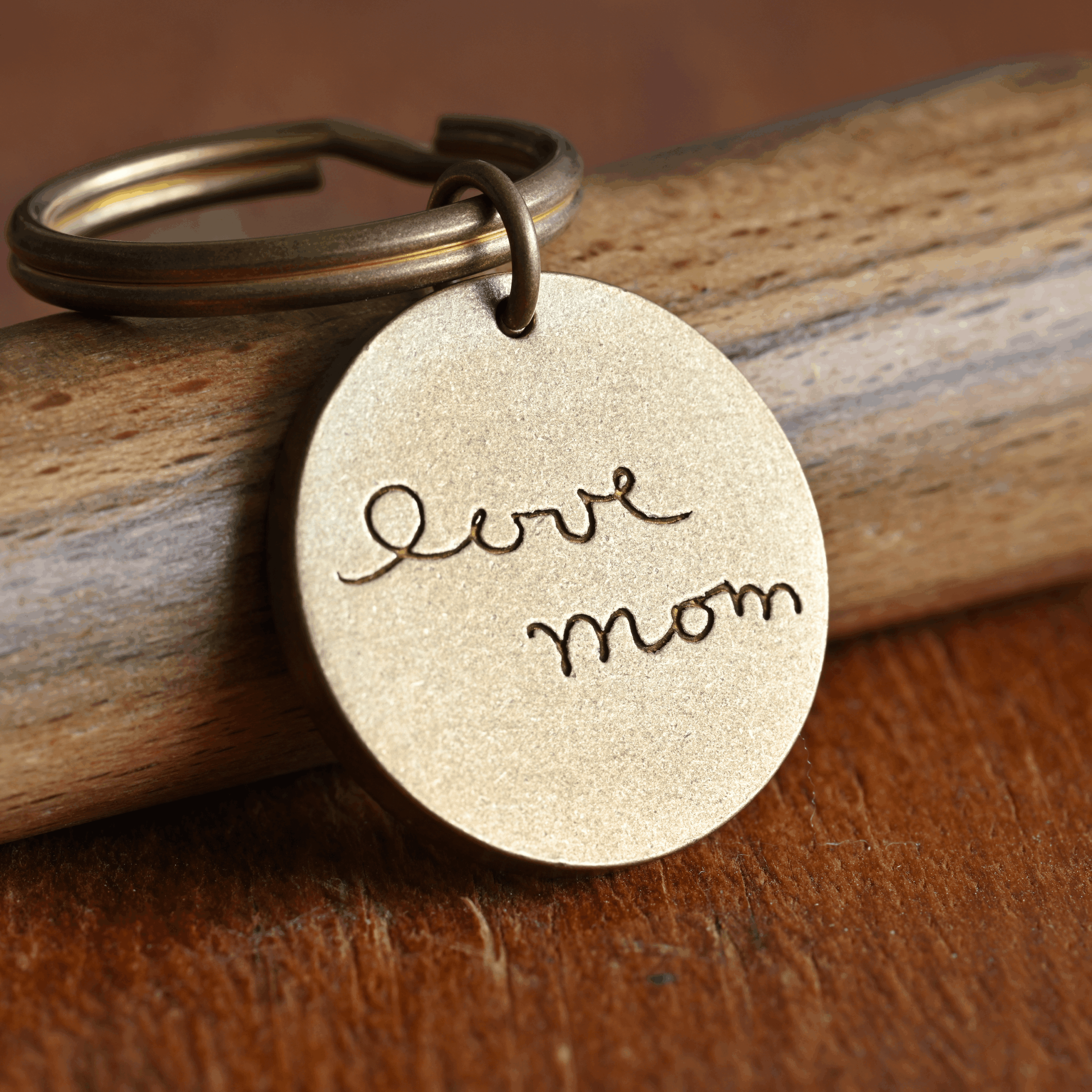 Bronze keychain with love mom engraving on a wooden surface, perfect for sentimental Mother's Day gift.