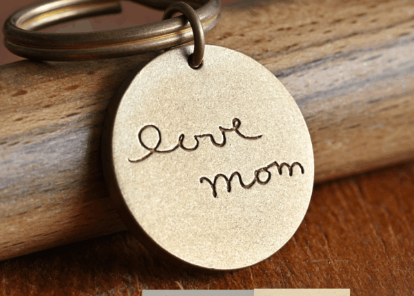 Engraved keychain with love mom script on wood surface, sentimental gift for mothers.