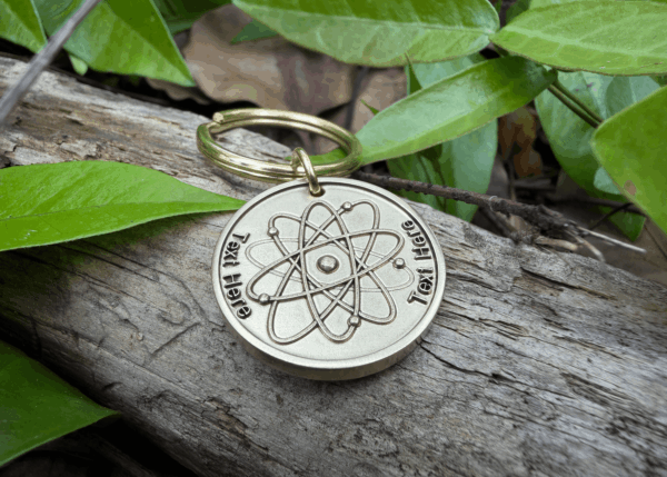 Keychain with engraved atom symbol on log with leaves; customizable text area Text Here.