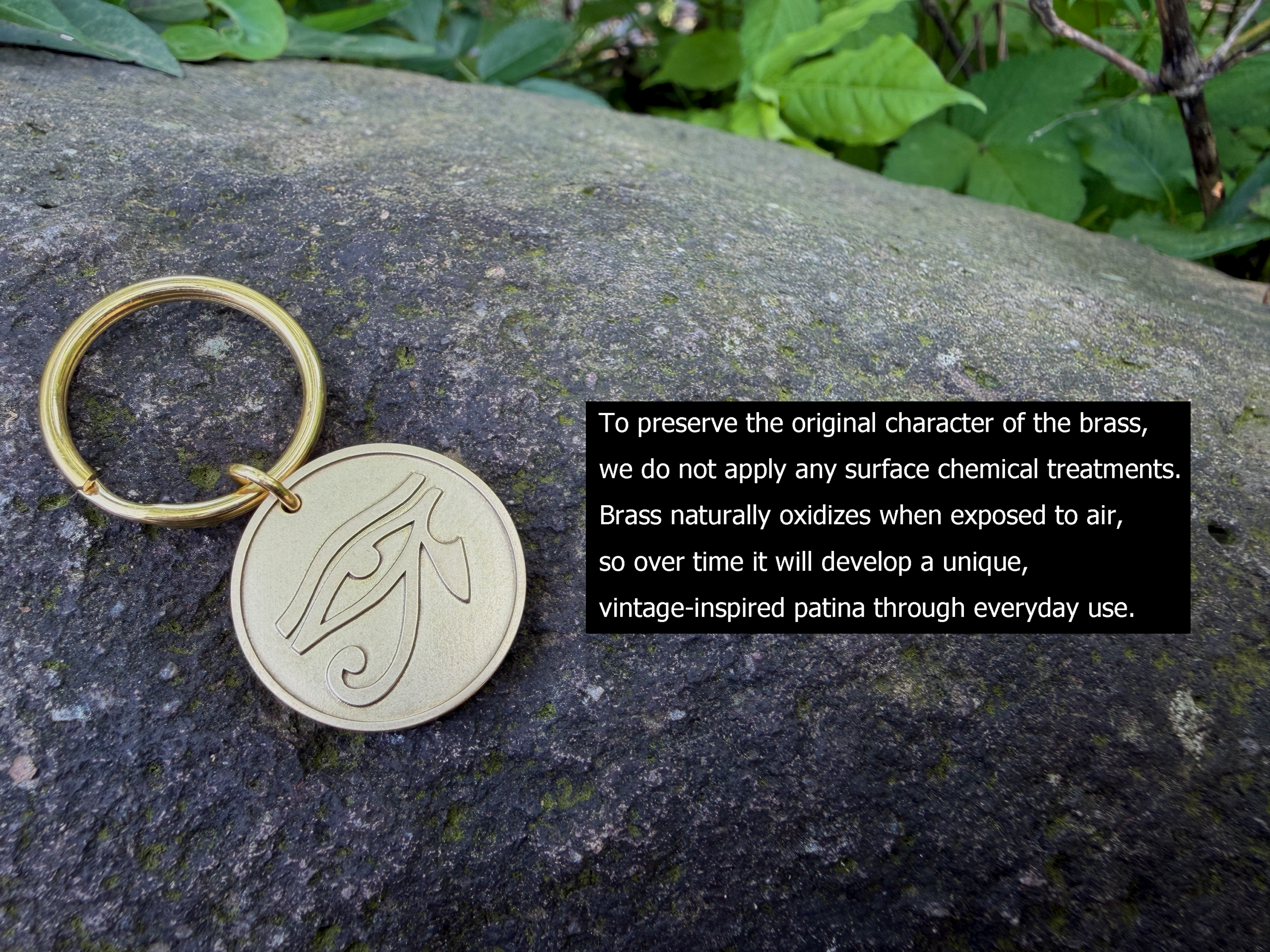 Brass keychain with Eye of Horus engraving on a rock, showcasing a natural patina development over time.