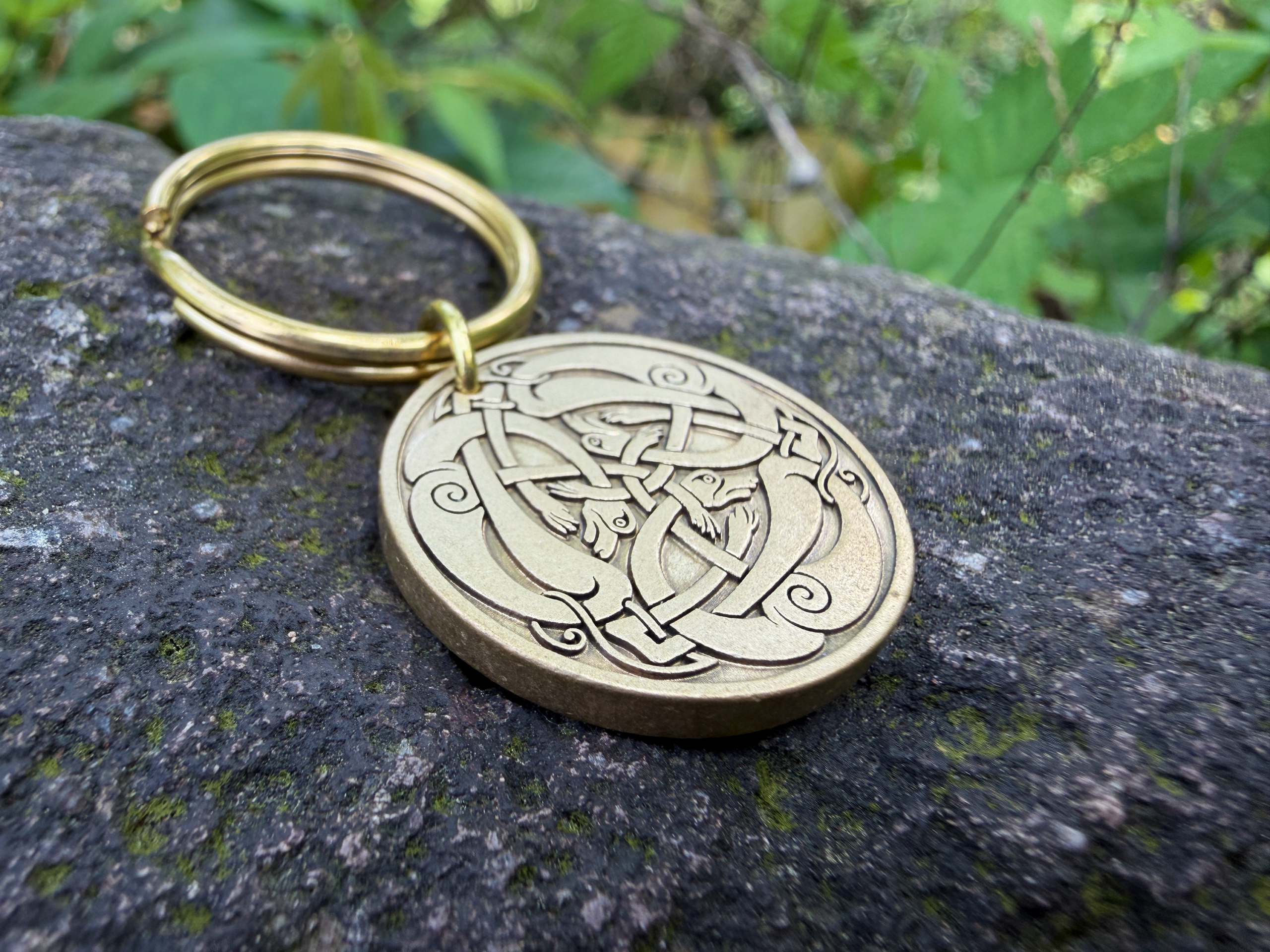 Celtic knot engraved keychain on stone with intricate loops and swirls design, gold finish, natural background.