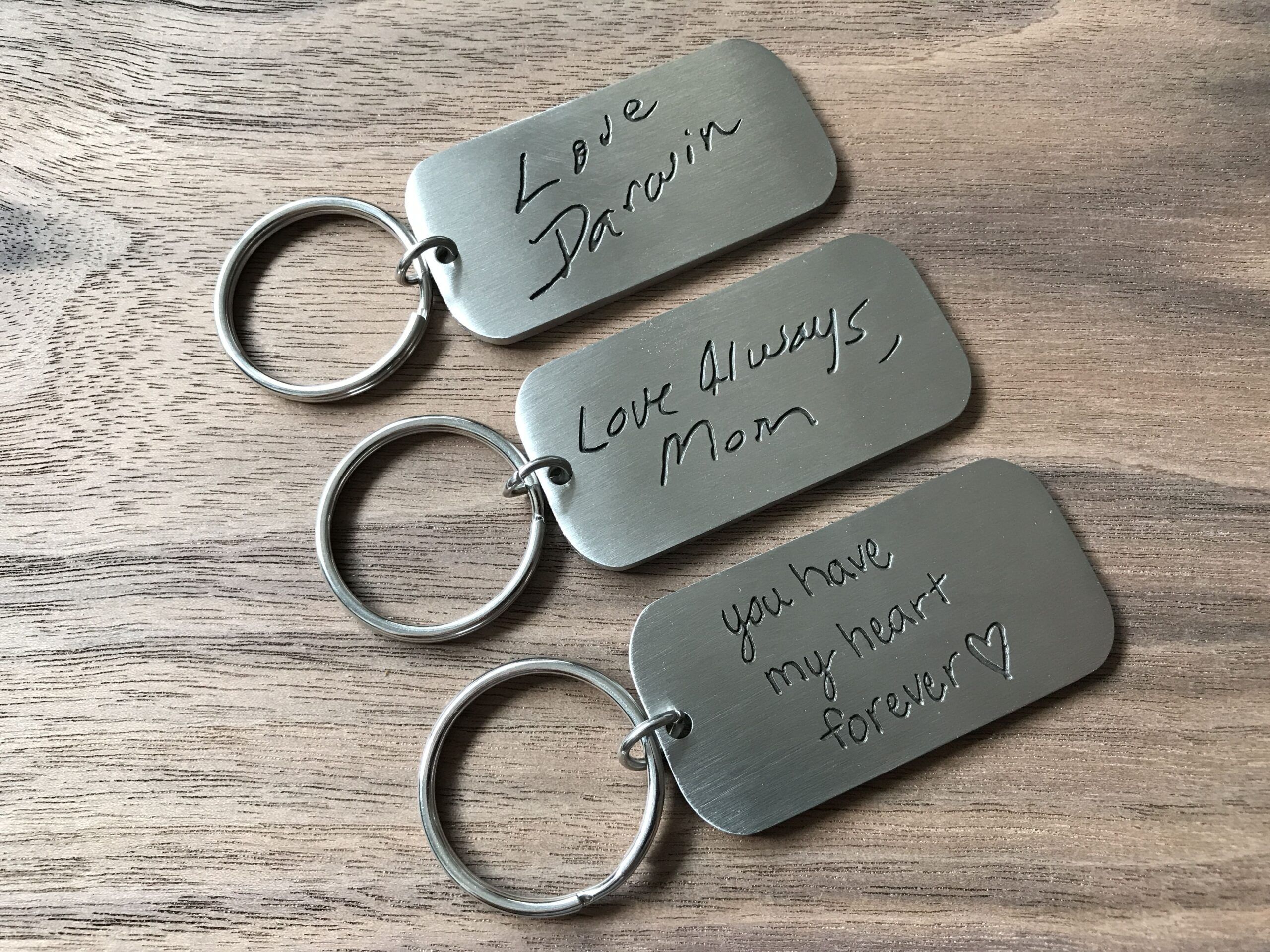 Three silver tag keychains with engravings: Love, Darwin, Love Always, Mom, you have my heart forever.