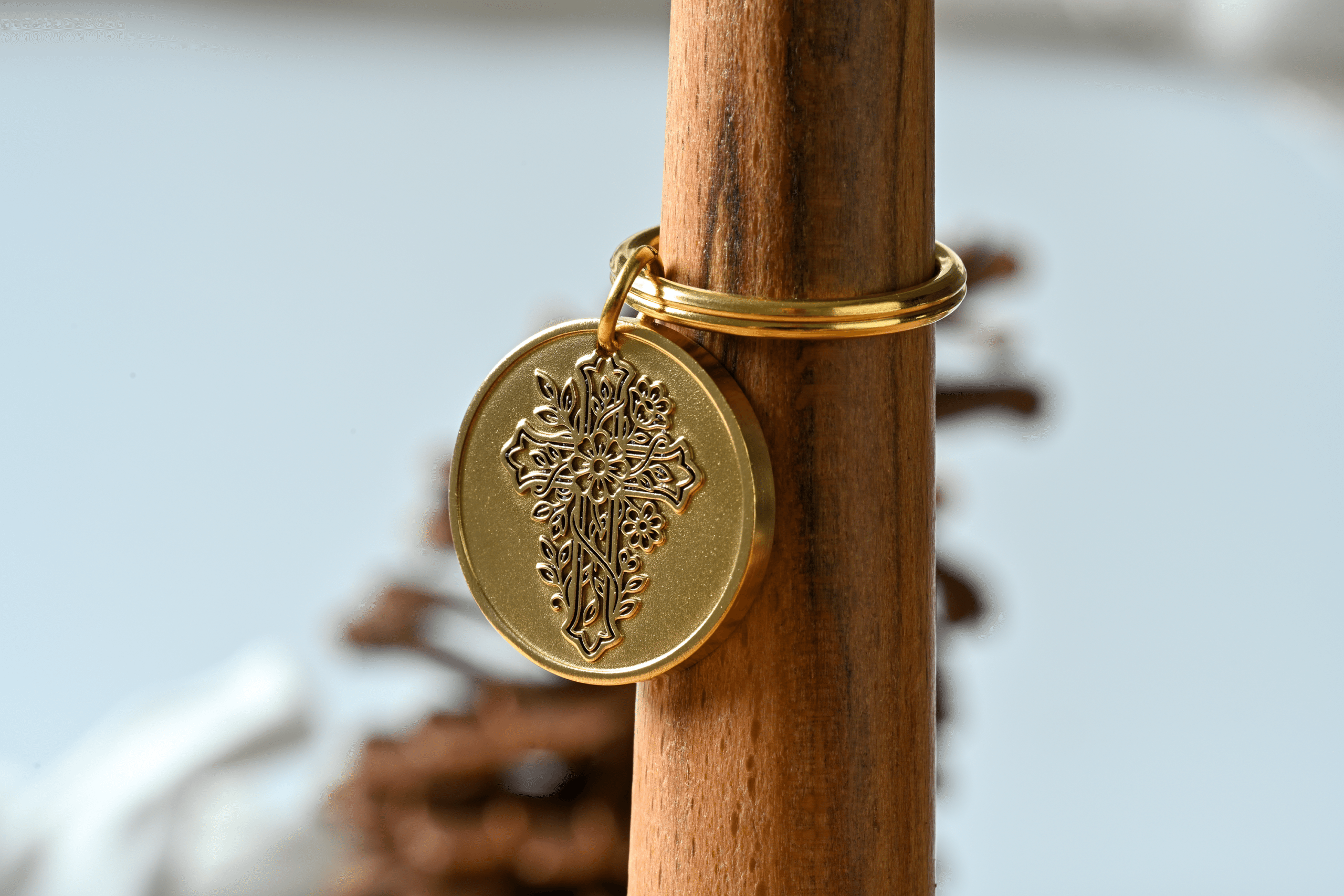 Gold circular pendant featuring an intricate embossed floral cross design