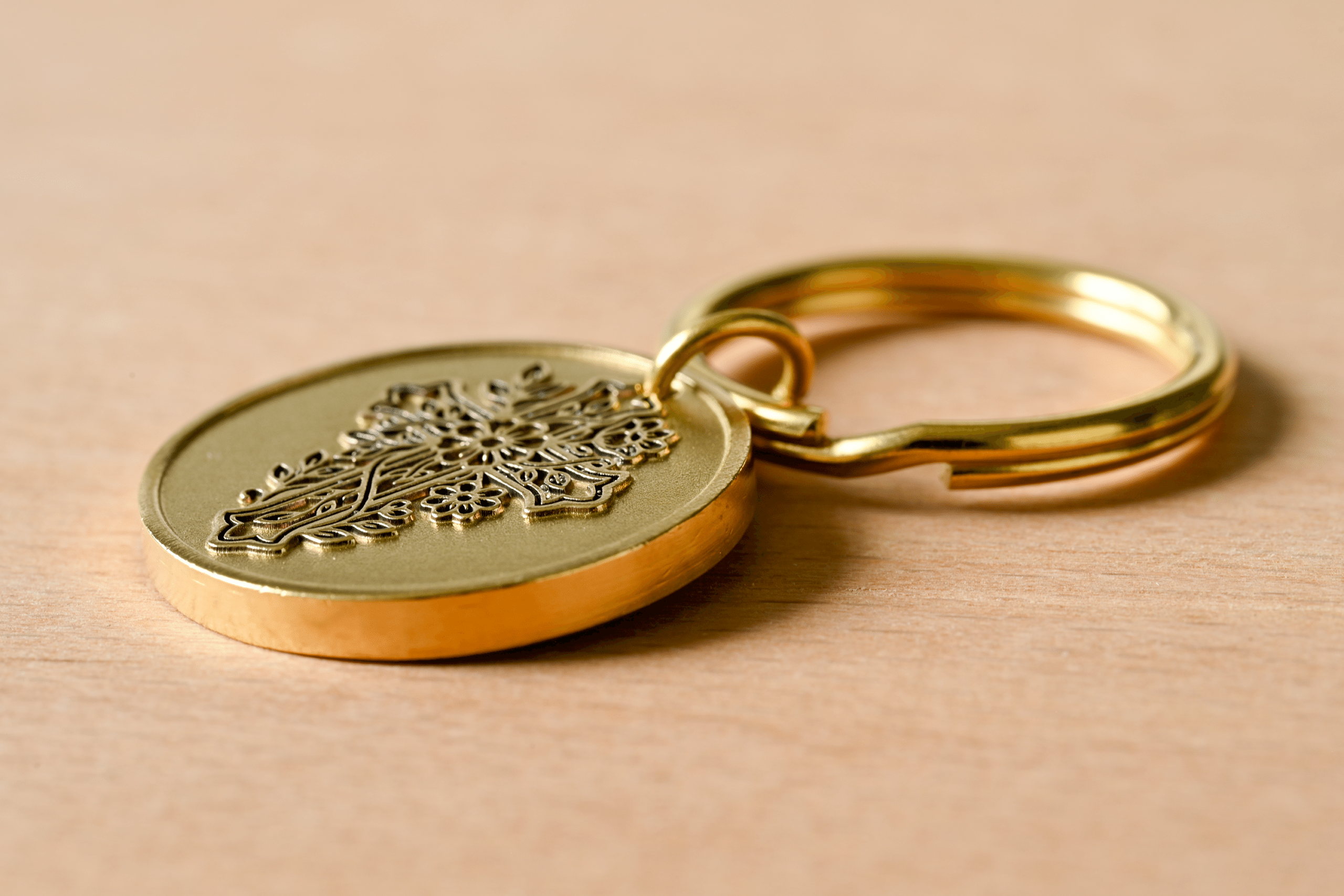 Gold keychain featuring a circular medallion with an embossed floral cross design