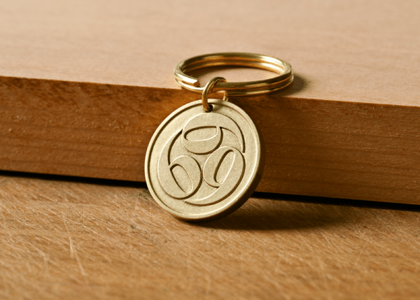 Brass keychain with a circular medallion featuring a stylized triple-swirl design