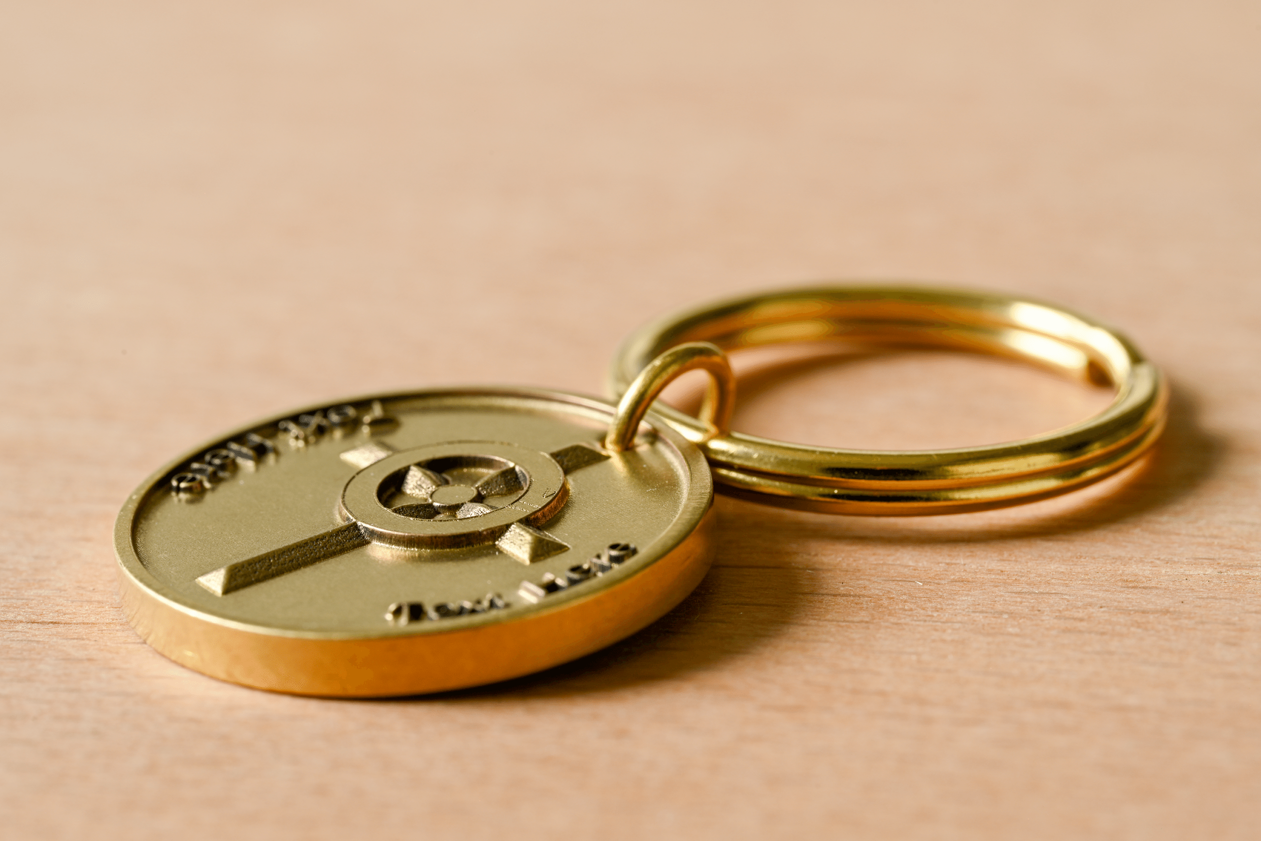 Gold keychain with a circular medallion featuring an embossed cross design on a wooden surface