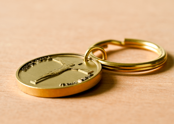 Gold-colored keychain with a circular medallion featuring a crucifix