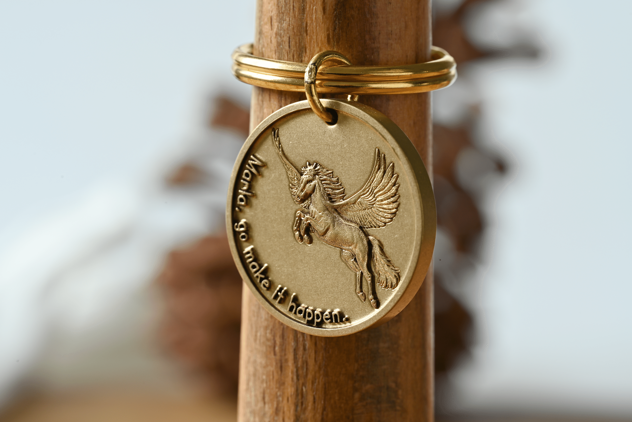 Gold keychain tag featuring a Pegasus and the engraved text: Marla, go make it happen