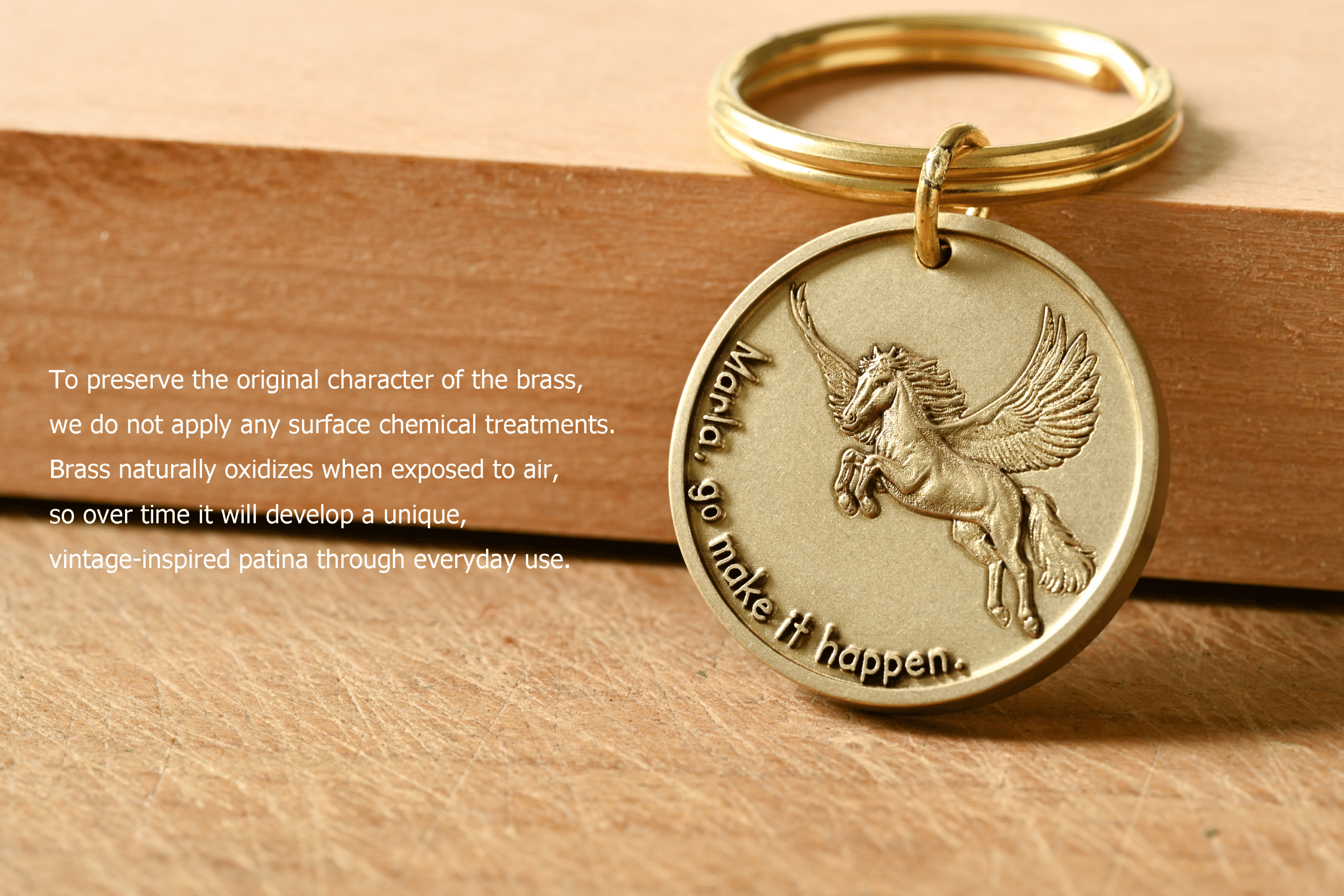 Brass keychain with an embossed Pegasus and engraving: Marla, go make it happen. Text explains brass develops a patina