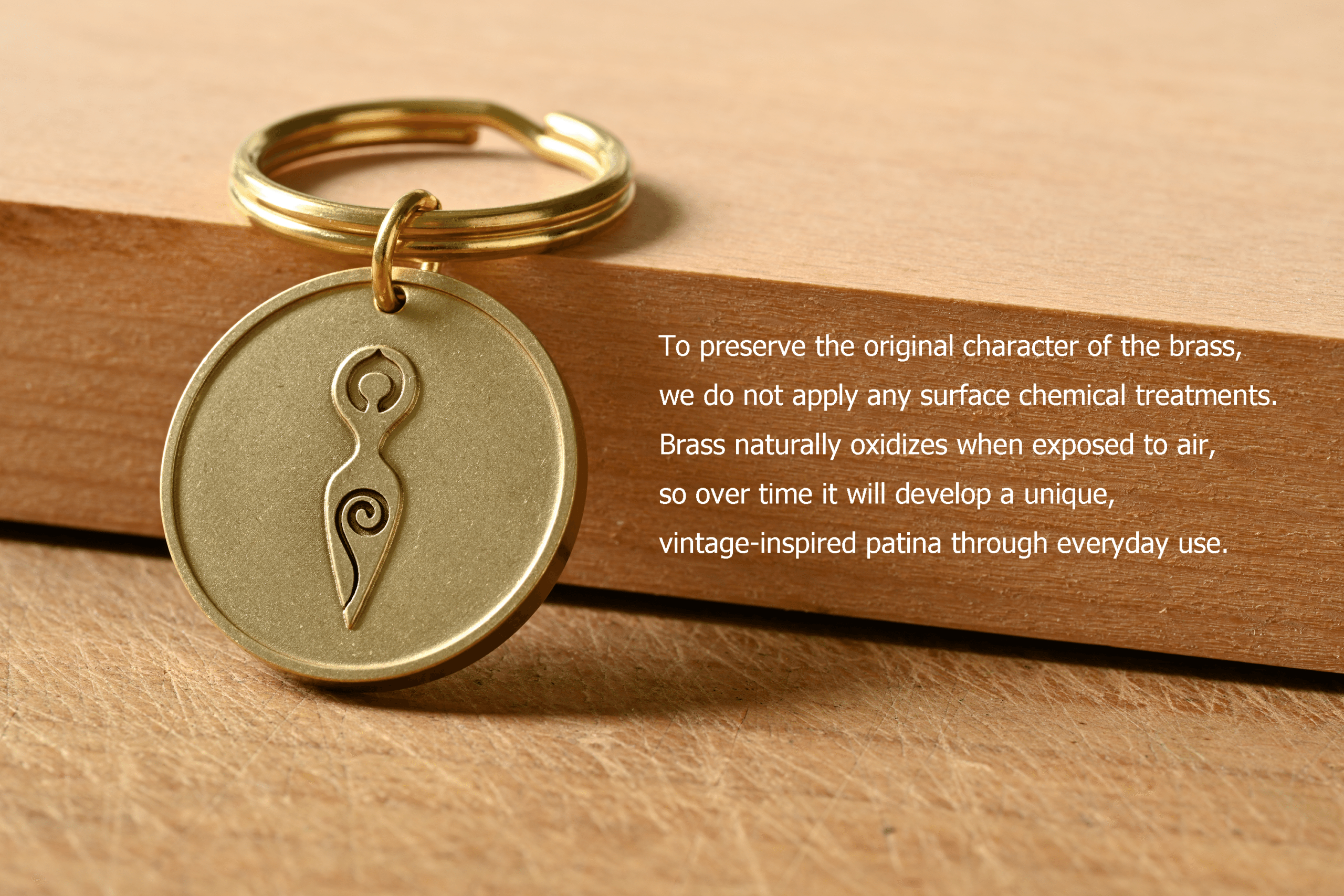 Brass keychain with a spiral goddess symbol. Text: To preserve the original character of the brass, we do not apply any surface chemical treatments. Brass naturally oxidizes when exposed to air, so over time it will develop a unique, vintage-inspired patina through everyday use