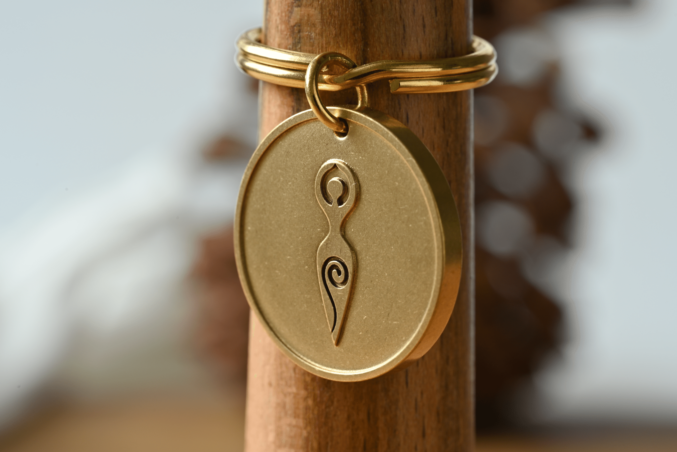 Gold round keychain featuring an embossed spiral goddess symbol