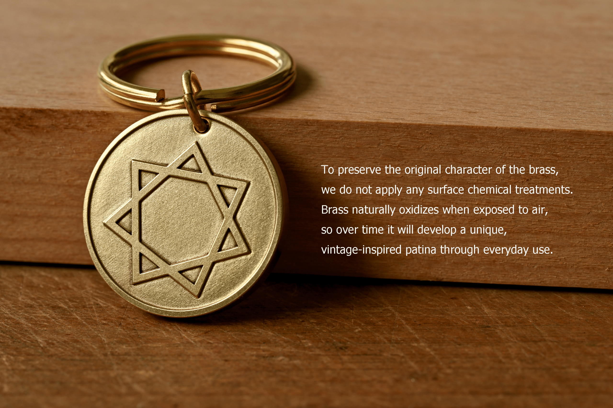 Brass keychain engraved with an seven-pointed star resting on a wooden surface, with text detailing how untreated brass naturally oxidizes over time to develop a unique vintage-inspired patina through everyday use