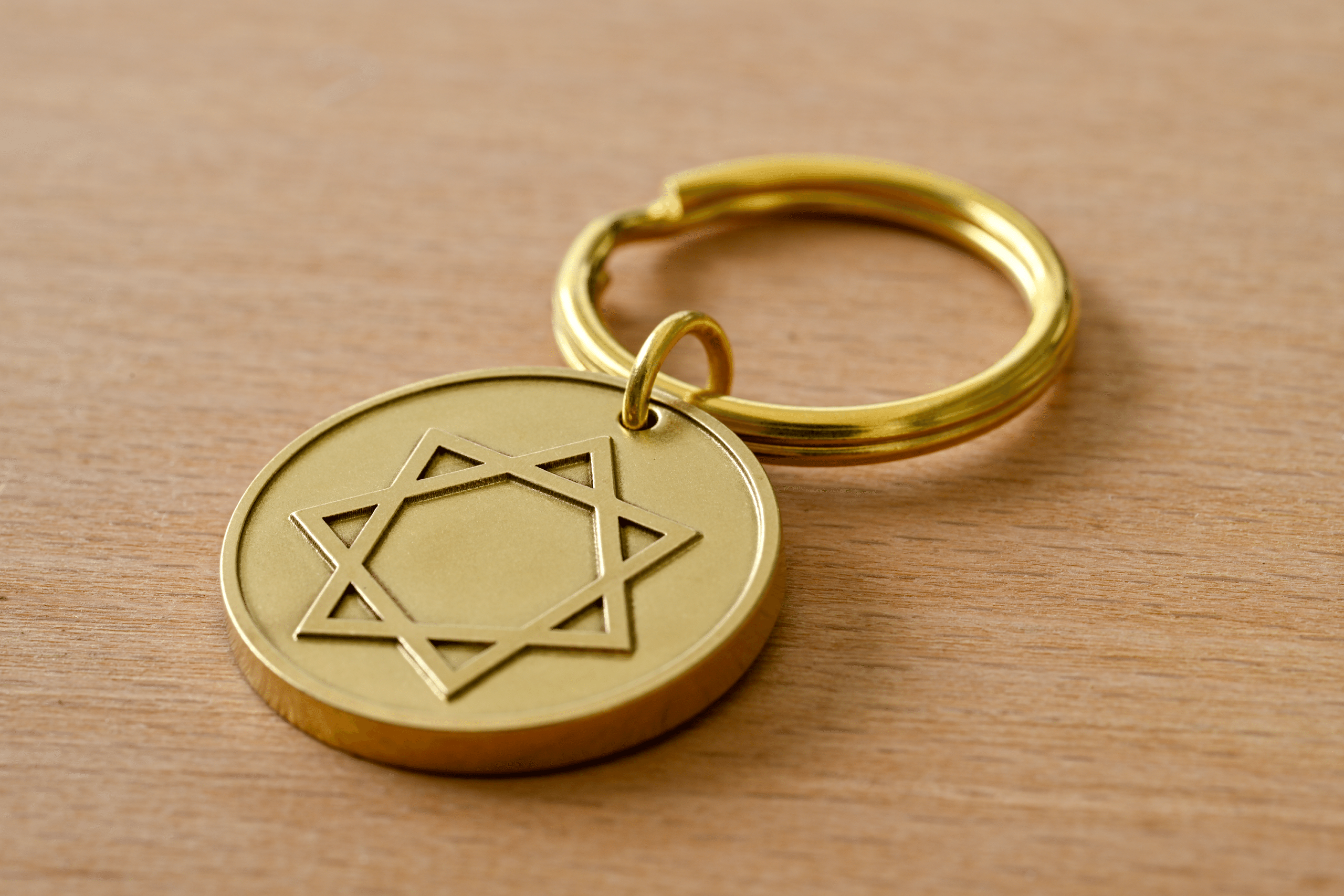 Gold round keychain tag engraved with an seven-pointed star, resting on a wooden surface