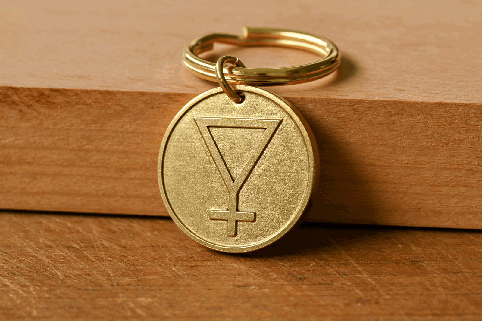 Brass circular keychain tag engraved with an inverted triangle and cross symbol