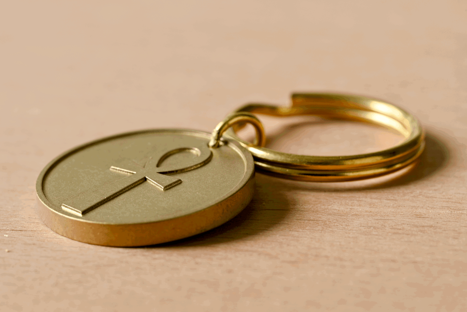 Brass keychain with a round medallion featuring an ankh symbol on a wooden surface