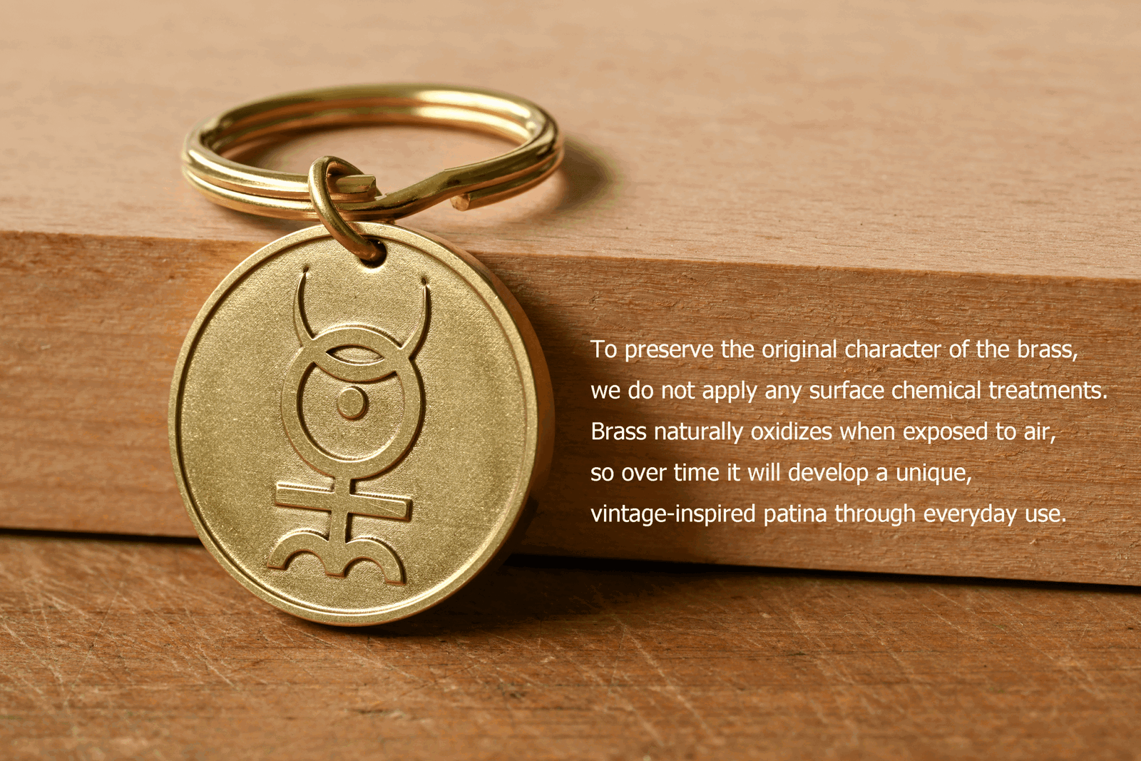 Brass keychain with an engraved symbol next to text explaining that untreated brass naturally oxidizes to develop a unique patina over time