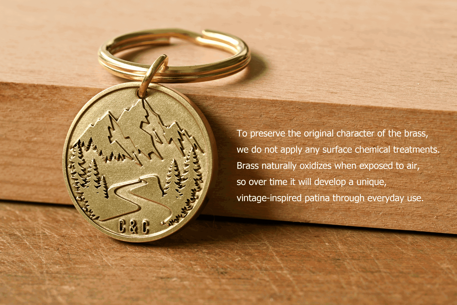 Brass mountain keychain stamped C&C beside text explaining that to preserve the original character of the brass, no surface chemical treatments are applied, so it naturally oxidizes and develops a unique patina over time