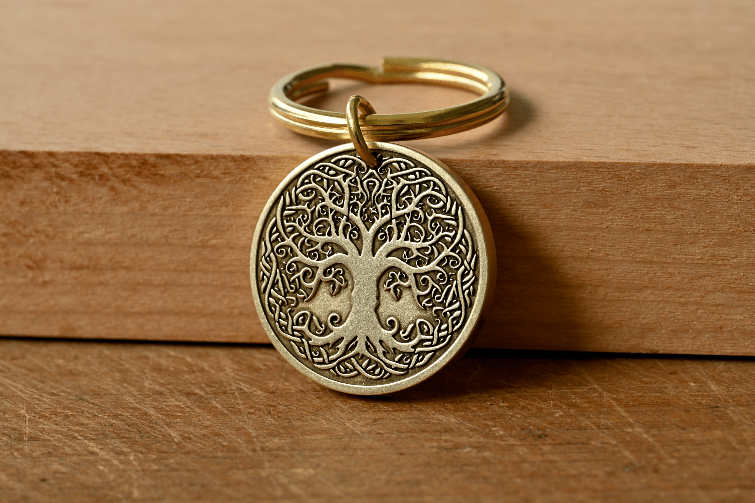 Brass keychain with a circular pendant featuring an intricate Tree of Life design on a wooden background