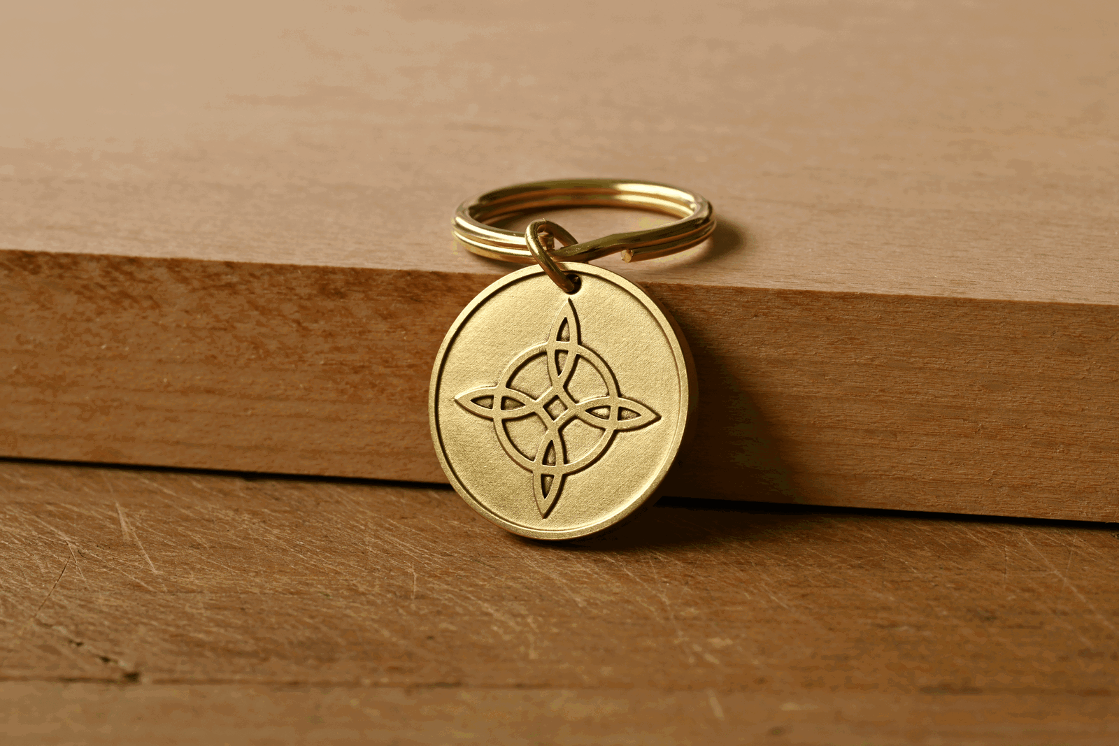 Brass circular keychain pendant featuring an engraved Witch's knot symbol, resting against a wooden surface