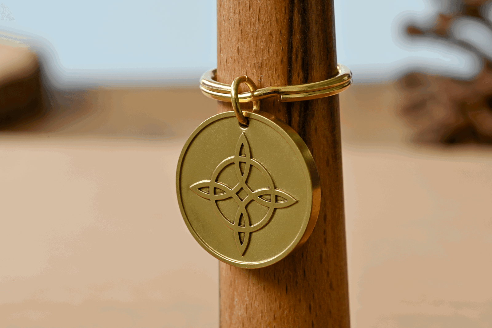 Gold circular keychain tag featuring an engraved witch's knot design